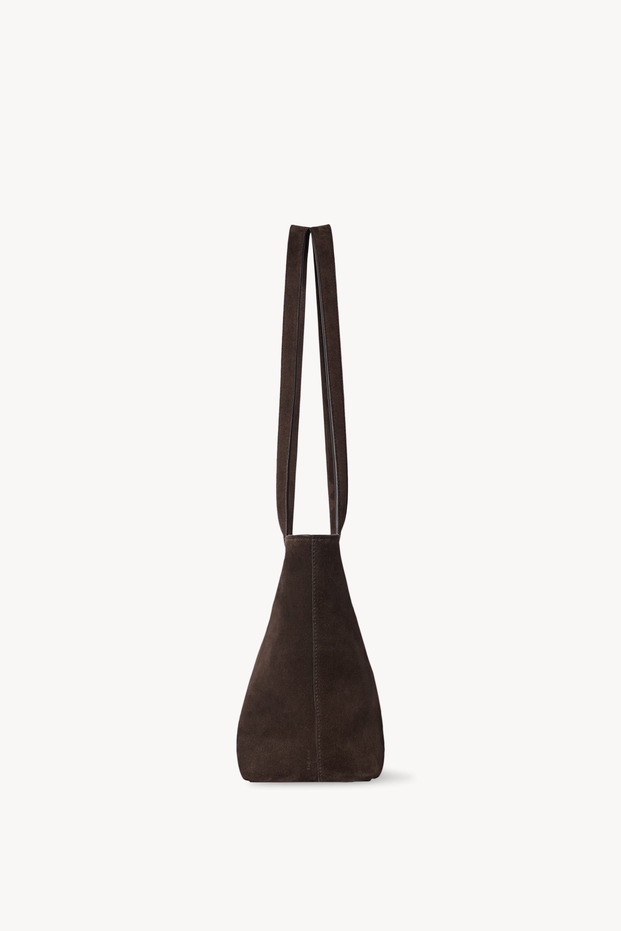 Side view of the dark brown The Row Parker Bag showing its tapered profile